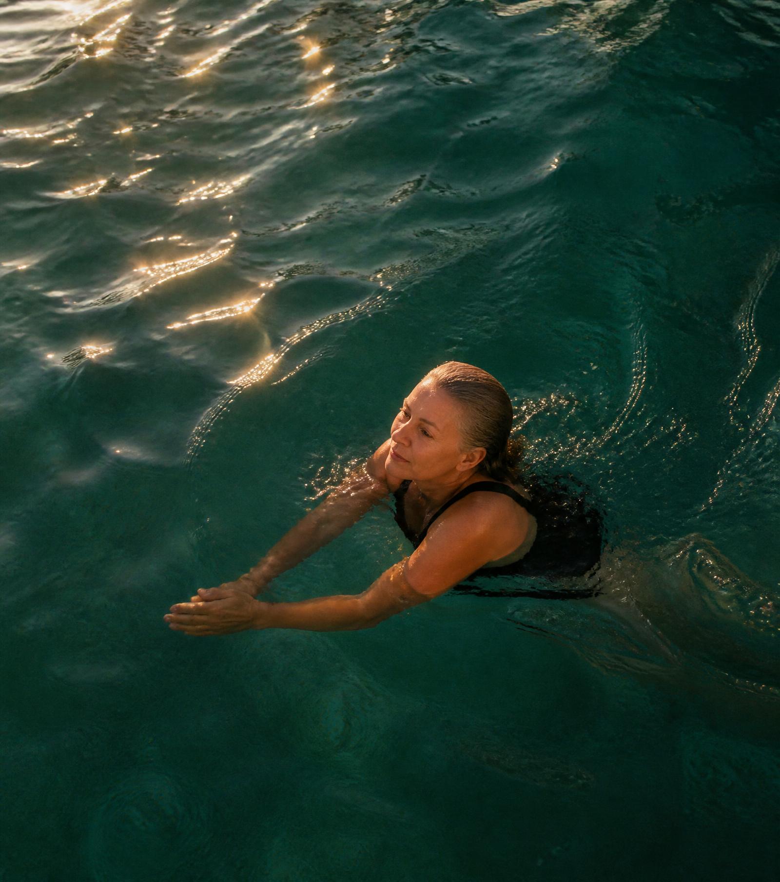 Mulher madura nadando calmamente em uma piscina ao amanhecer